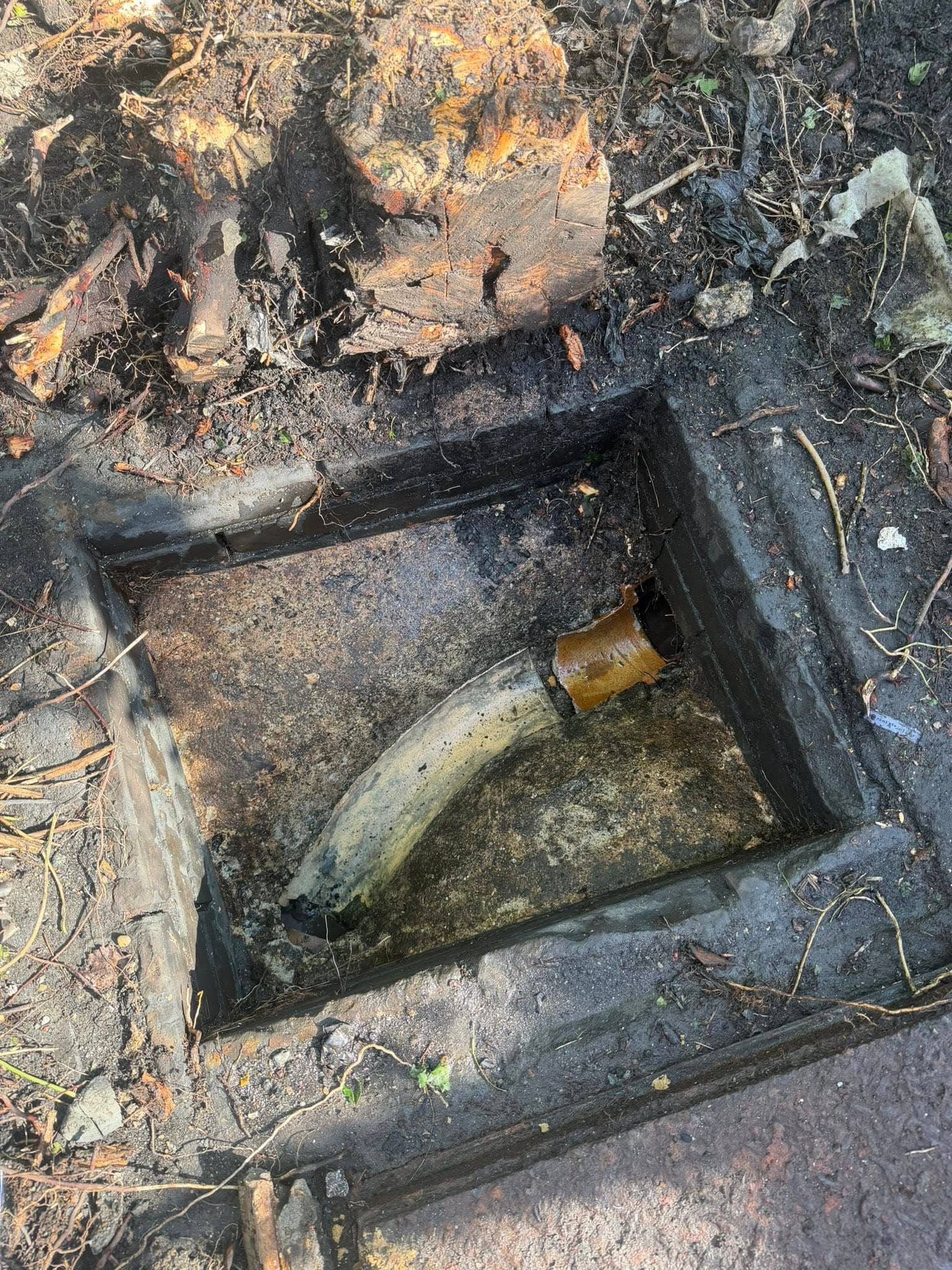 Drainage chamber exposed during investigation showing pipework and standing water